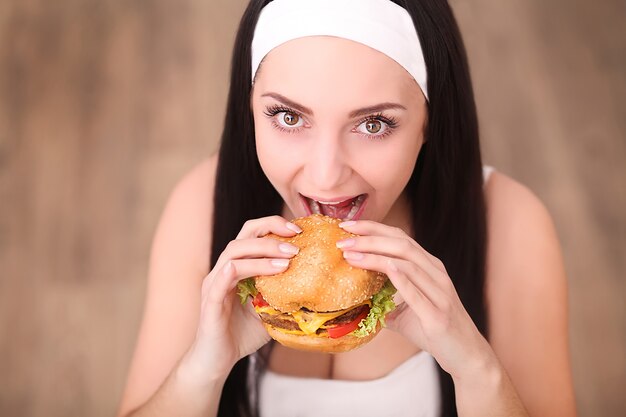 Mulher jovem comendo um hambúrguer