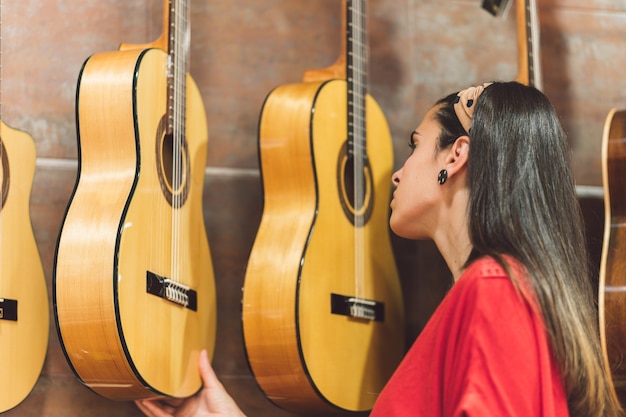 Mulher jovem comprando guitarras para comprar em uma loja