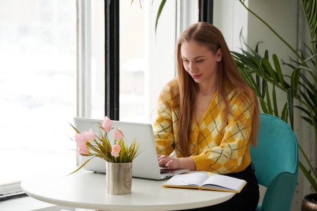 Mulher jovem confiante em casual wear inteligente trabalhando no laptop