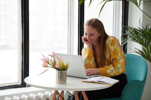 Mulher jovem confiante em casual wear inteligente trabalhando no laptop