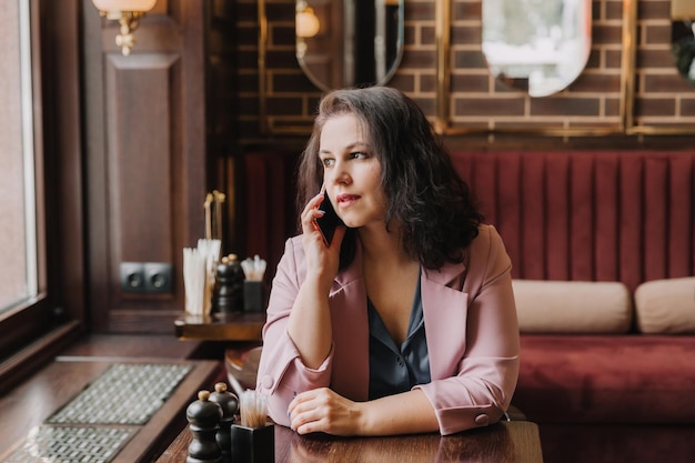 Mulher jovem confiante segurando um smartphone falando ao telefone mulher de negócios consultando um cliente