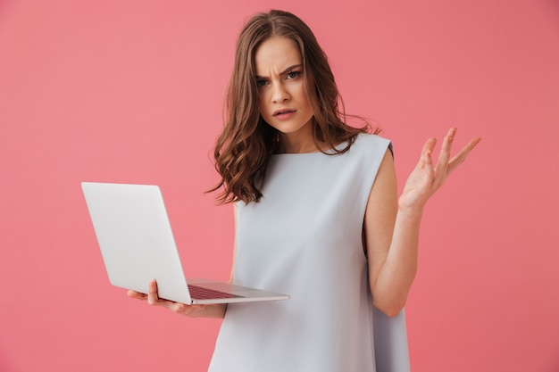 Mulher jovem confusa usando o computador portátil.