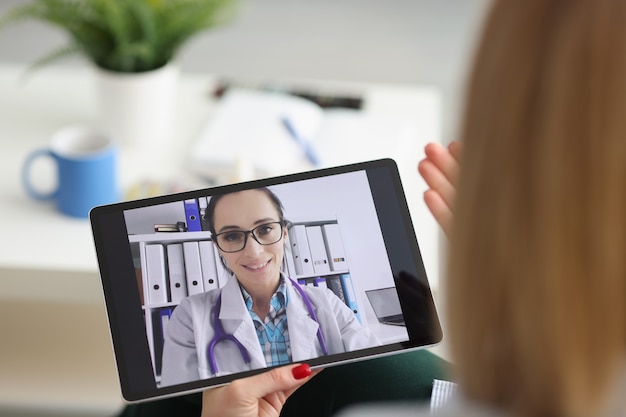 Foto mulher jovem consulta com terapeuta familiar por videochamada on-line no tablet com o médico