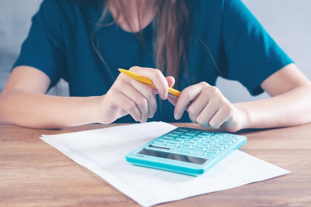 Foto mulher jovem contando com uma calculadora
