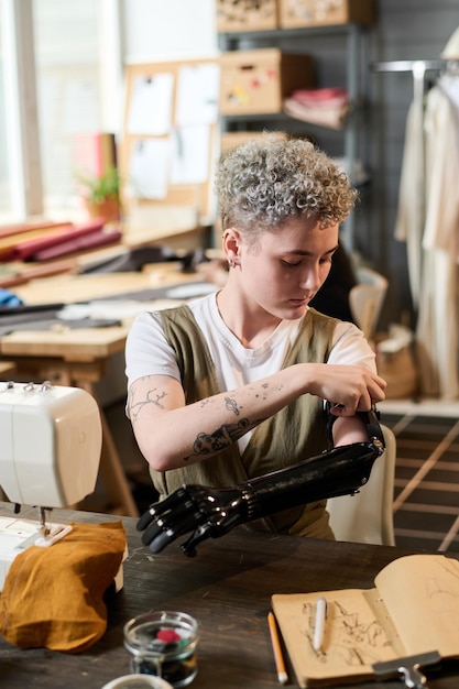 Mulher jovem contemporânea encaixando prótese de braço mioelétrico durante o trabalho