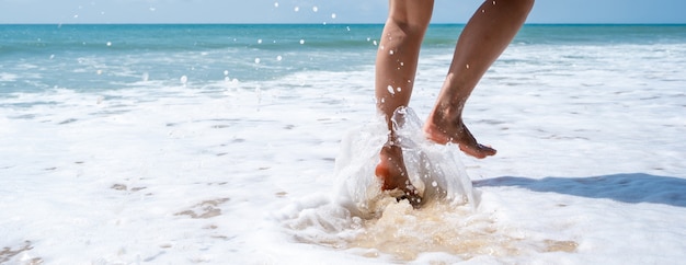 Mulher jovem correndo na praia tropical em um dia ensolarado, conceito de férias de verão