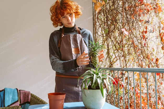 Mulher jovem cuida de planta de abacaxi em vaso de flores