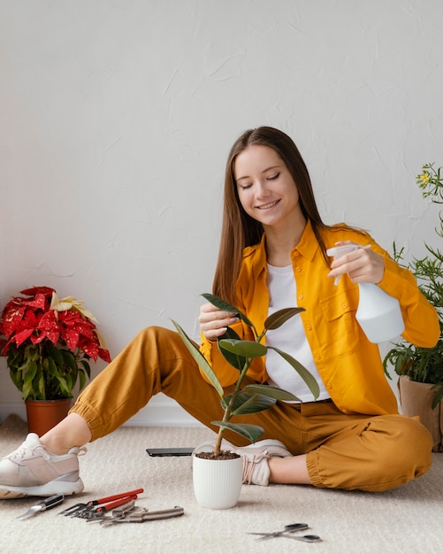 Mulher jovem cuidando de suas plantas em casa