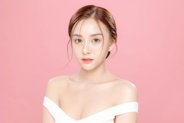 Mulher jovem de beleza asiática puxou o cabelo para trás com estilo de maquiagem coreana no rosto e pele perfeita em fundo rosa isolado Tratamento facial Cosmetologia cirurgia plástica