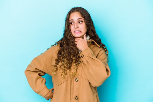 Mulher jovem de cabelo encaracolado caucasiano isolada tocando a parte de trás da cabeça, pensando e fazendo uma escolha.