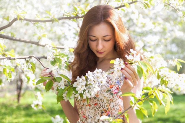 Mulher jovem de cabelo ruivo perto de árvore florescendo macia branca. humor onírico de fadas da primavera e do verão. Linda senhora romântica sorrindo noiva, casamento. Copie o fundo do espaço.