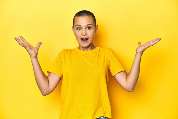 Mulher jovem de camisola amarela com fundo de estúdio amarelo gritando para o céu olhando para cima frustrada