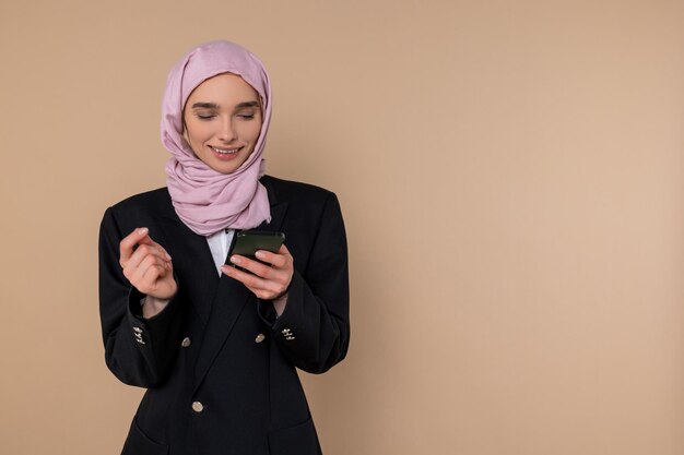 Mulher jovem de fato preto com um telefone nas mãos.