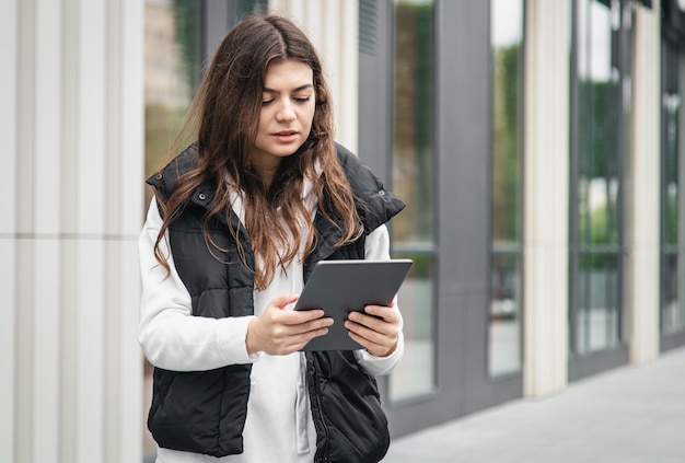 Mulher jovem de negócios com um tablet no fundo do edifício