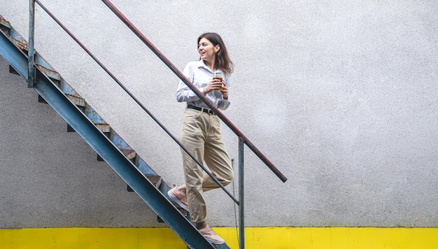 Foto mulher jovem de negócios perto das escadas com uma xícara de café