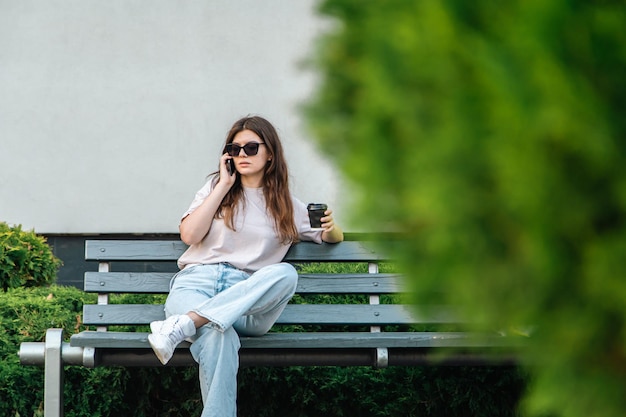 Mulher jovem de negócios senta-se em um banco e fala ao telefone