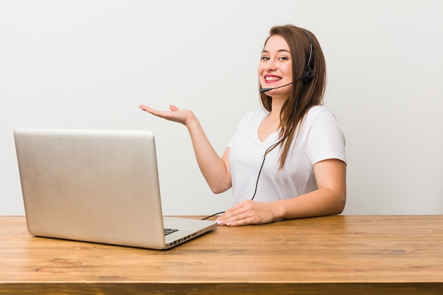 Mulher jovem de operador de telemarketing segurando um espaço de cópia na palma da mão.