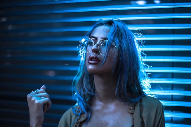 Mulher jovem de pé à janela à noite.