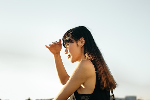 Mulher jovem de pé contra o céu claro