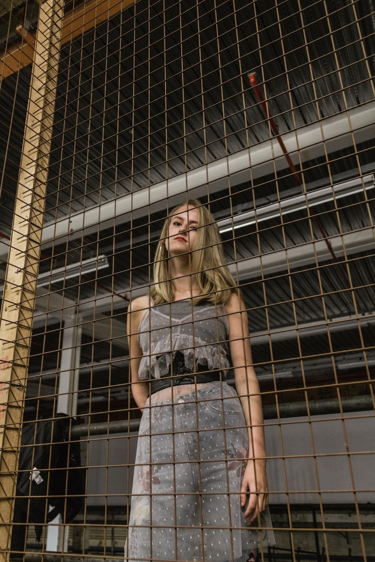 Foto mulher jovem de pé contra uma grade de metal