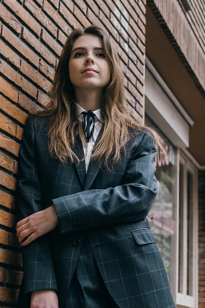 Foto mulher jovem de pé junto à parede de tijolos