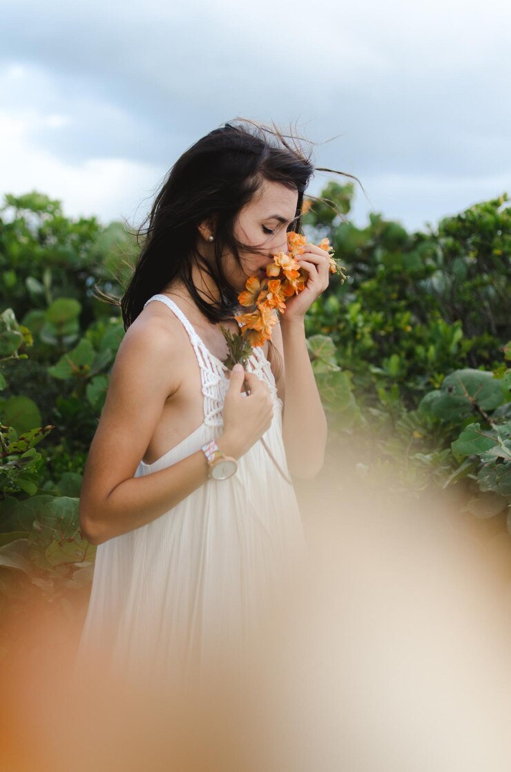 Foto mulher jovem de pé junto a plantas contra o céu