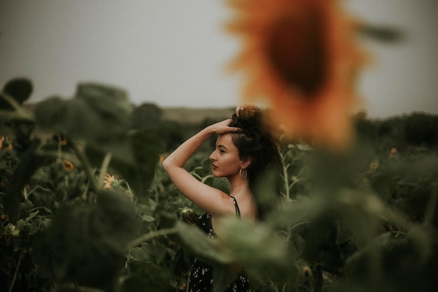 Mulher jovem de pé no meio de girassóis no campo