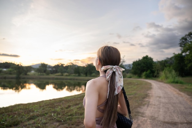 Foto mulher jovem de pé perto do lago durante o pôr-do-sol bela natureza