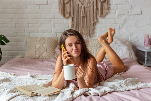 Mulher jovem de pijama rosa deitada na cama em casa