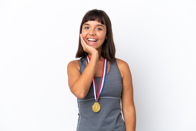 Mulher jovem de raça mista com medalhas isoladas no fundo branco com surpresa e expressão facial chocada