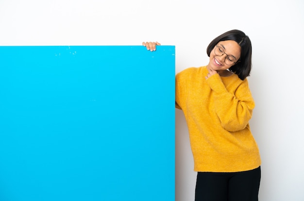 Mulher jovem de raça mista com um grande cartaz azul isolado no fundo branco, olhando para cima enquanto sorri