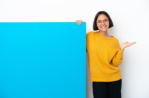 Mulher jovem de raça mista com um grande cartaz azul isolado no fundo branco segurando o imaginário de copyspace na palma da mão para inserir um anúncio