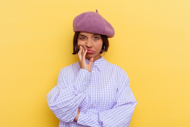 Mulher jovem de raça mista com uma boina isolada em fundo amarelo que está entediada, cansada e precisa de um dia de relaxamento.