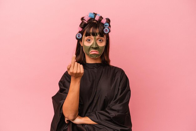 Mulher jovem de raça mista esperando em um salão Beaty isolado no fundo rosa apontando com o dedo para você como se estivesse convidando para se aproximar