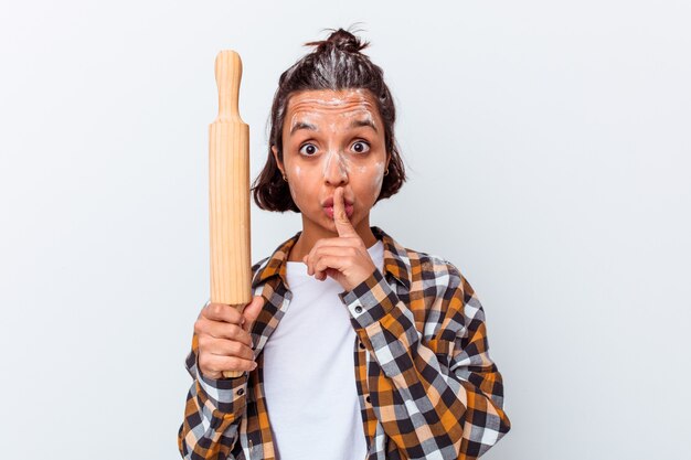 Mulher jovem de raça mista fazendo pão isolado no fundo branco, mantendo um segredo ou pedindo silêncio.