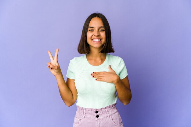 Mulher jovem de raça mista fazendo um juramento, colocando a mão no peito.