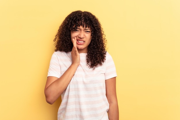 Mulher jovem de raça mista isolada em fundo amarelo com uma forte dor molar de dentes