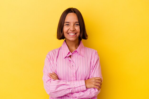 Mulher jovem de raça mista isolada em fundo amarelo, rindo e se divertindo.