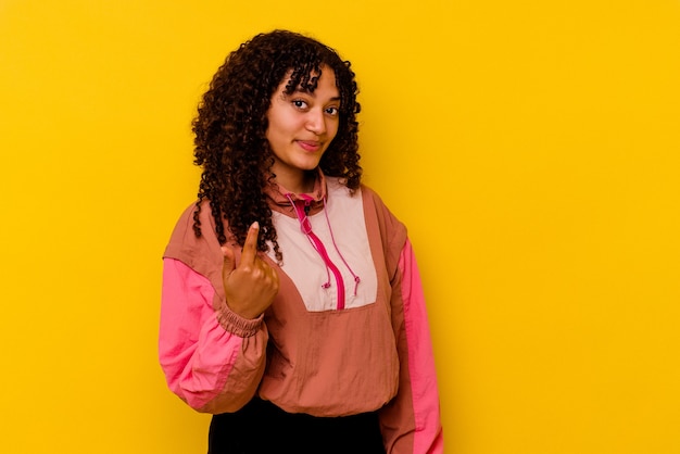 Mulher jovem de raça mista isolada em fundo rosa apontando com o dedo para você como se fosse um convite para se aproximar.