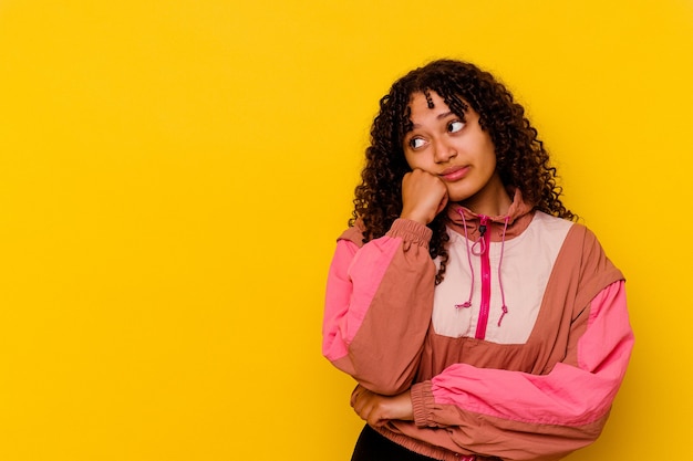 Mulher jovem de raça mista isolada em fundo rosa que se sente triste e pensativa, olhando para o espaço da cópia.