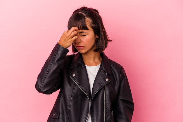 Mulher jovem de raça mista isolada em um fundo rosa, tendo uma dor de cabeça, tocando a frente do rosto.