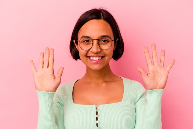 Foto mulher jovem de raça mista isolada na rosa mostrando o número dez com as mãos.
