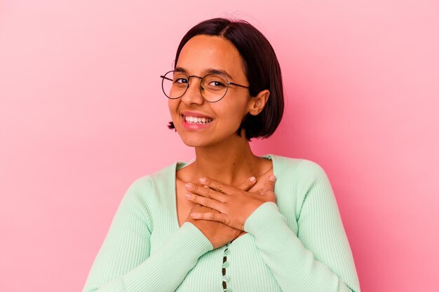 Mulher jovem de raça mista isolada na rosa rindo mantendo as mãos no coração, o conceito de felicidade.