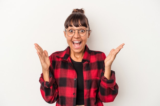 Mulher jovem de raça mista isolada no fundo branco, comemorando uma vitória ou sucesso, ele fica surpreso e chocado.