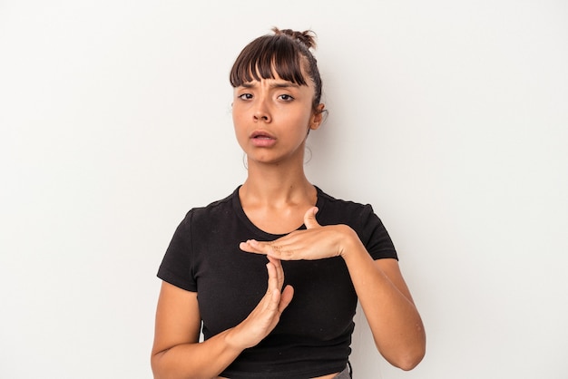 Mulher jovem de raça mista isolada no fundo branco, mostrando um gesto de tempo limite.