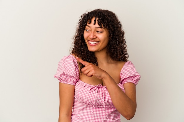 Mulher jovem de raça mista isolada no fundo branco parece de lado sorrindo, alegre e agradável.