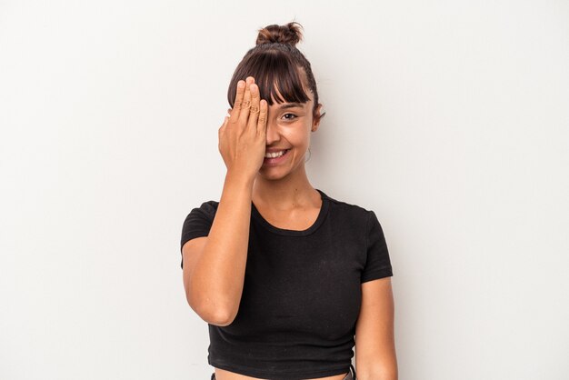 Foto mulher jovem de raça mista isolada no fundo branco, se divertindo, cobrindo metade do rosto com a palma da mão.