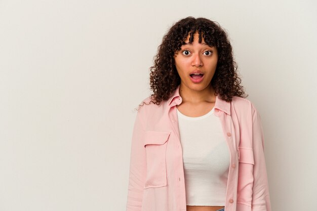 Mulher jovem de raça mista isolada no fundo branco, sendo chocada por causa de algo que ela viu.