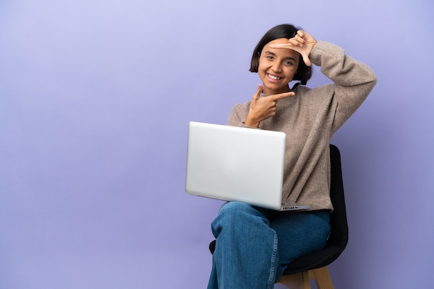 Mulher jovem de raça mista sentado em uma cadeira com laptop isolado focalizando o rosto. Símbolo de enquadramento