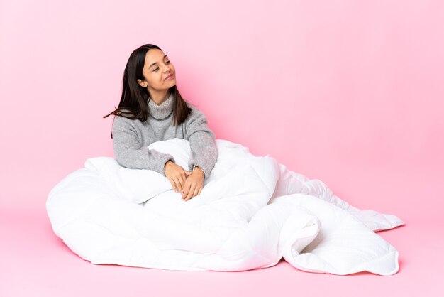 Mulher jovem de raça mista usando pijama, sentada no chão. Retrato